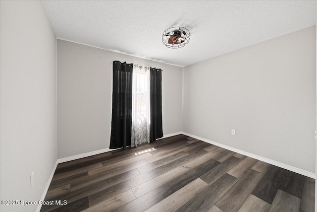 empty room featuring wood finished floors, baseboards, and a textured ceiling