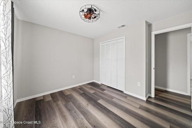 unfurnished bedroom with dark wood-style floors, baseboards, and a closet