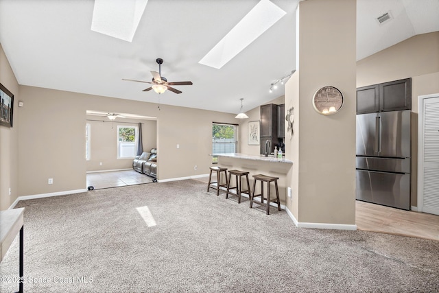1265 Giralda Cir NW, Palm Bay, FL 32907 - living area featuring a skylight, lofted ceiling, light colored carpet, baseboards, and a ceiling fan