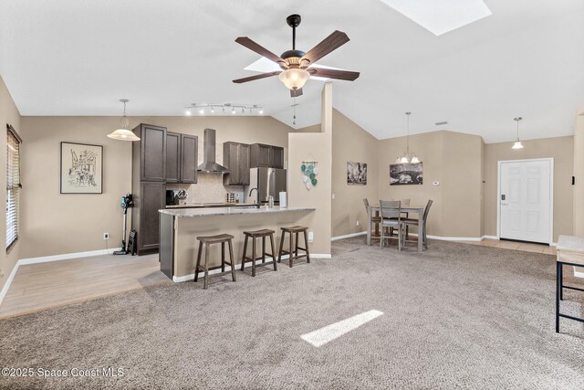 1265 Giralda Cir NW, Palm Bay, FL 32907 - kitchen featuring wall chimney exhaust hood, a breakfast bar area, vaulted ceiling, freestanding refrigerator, and hanging light fixtures