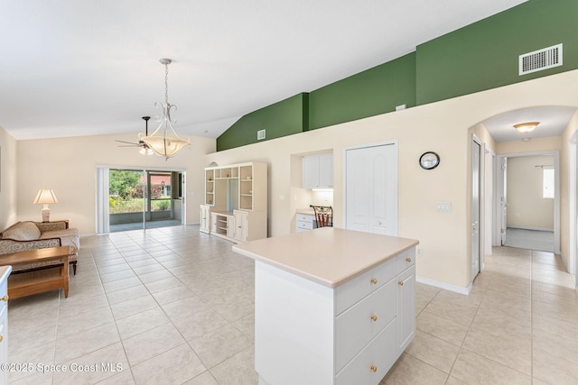 7175 Mendell Way, Melbourne, FL 32940 - kitchen with arched walkways, white cabinets, light tile patterned flooring, light countertops, and a kitchen island