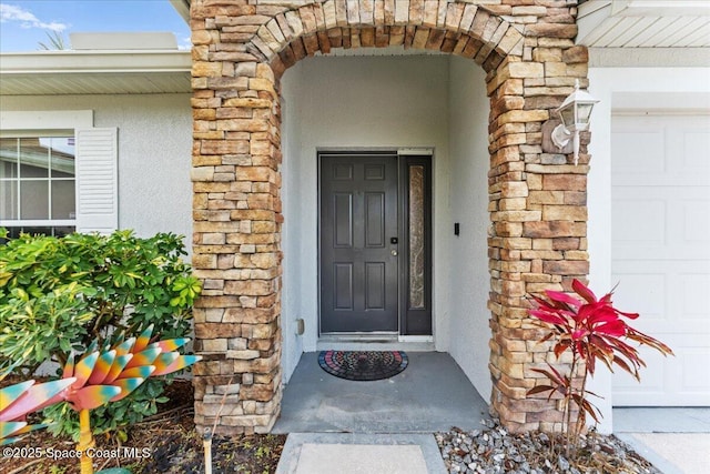 property entrance featuring stucco siding and stone siding