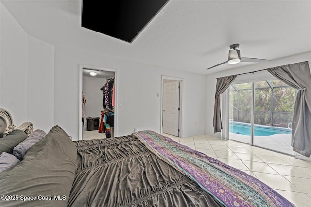 bedroom with access to exterior, tile patterned floors, a walk in closet, and a ceiling fan