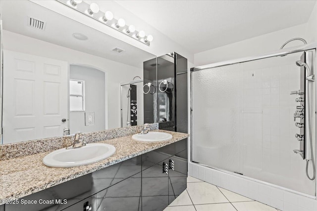 full bathroom featuring a shower stall, tile patterned flooring, and double vanity
