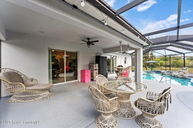 view of patio featuring a ceiling fan, a lanai, a pool with connected hot tub, and outdoor dining space