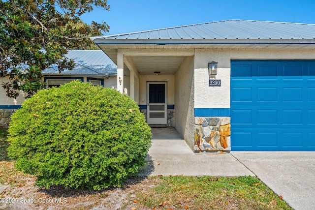 doorway to property with stucco siding, stone siding, and metal roof
