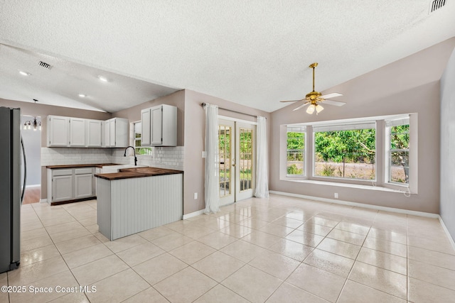 kitchen with lofted ceiling, open floor plan, a textured ceiling, light tile patterned floors, and a ceiling fan
