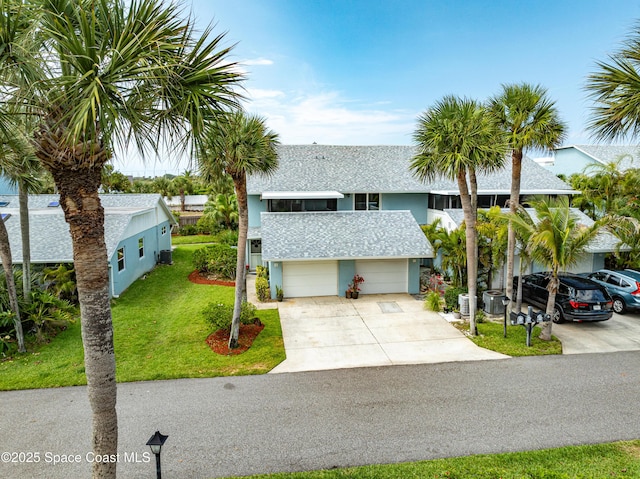 8 Cove Rd Unit 8-B, Melbourne Beach, FL 32951 - view of front of home featuring concrete driveway, stucco siding, a front lawn, an attached garage, and a shingled roof