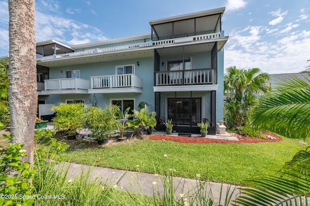 8 Cove Rd Unit 8-B, Melbourne Beach, FL 32951 - rear view of house featuring a balcony, a lawn, and stucco siding