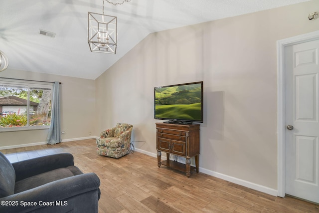 living room featuring baseboards, vaulted ceiling, wood finished floors, and visible vents