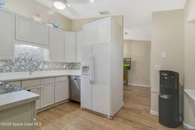 kitchen with white fridge with ice dispenser, visible vents, ceiling fan, decorative backsplash, and stainless steel dishwasher