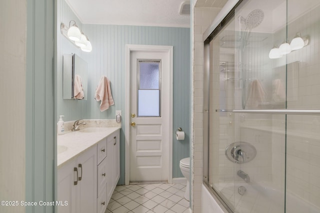 bathroom featuring double vanity, toilet, enclosed tub / shower combo, a sink, and tile patterned floors