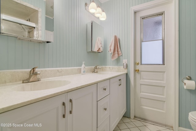 bathroom with double vanity, tile patterned floors, toilet, and a sink