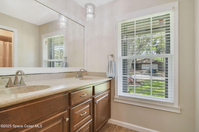 bathroom with a sink, double vanity, baseboards, and wood finished floors