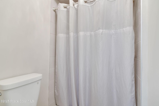 bathroom with toilet and a shower with shower curtain
