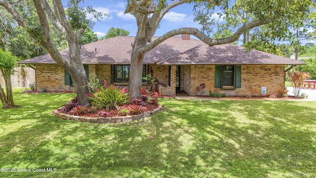 ranch-style house with a shingled roof, brick siding, fence, and a front yard