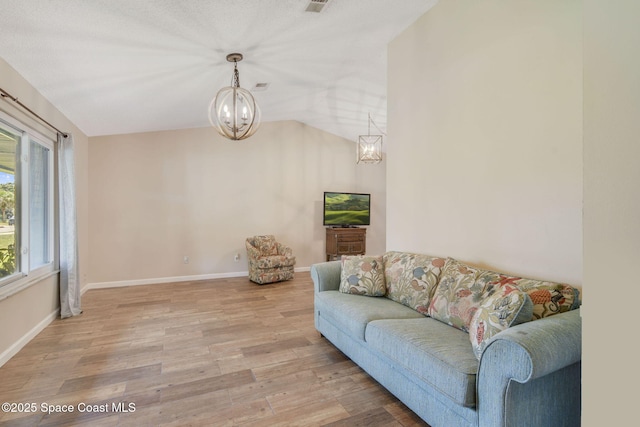 living room featuring an inviting chandelier, baseboards, and light wood-type flooring
