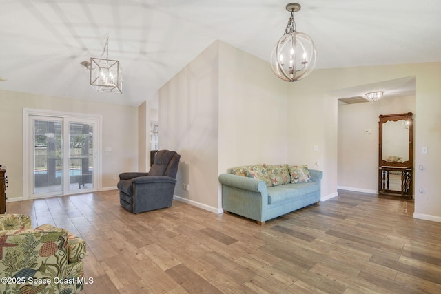 living area with baseboards, vaulted ceiling, an inviting chandelier, and wood finished floors