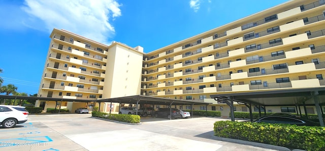 view of building exterior with covered and uncovered parking