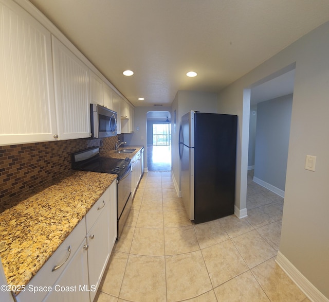 kitchen featuring stainless steel appliances, a sink, white cabinetry, decorative backsplash, and recessed lighting
