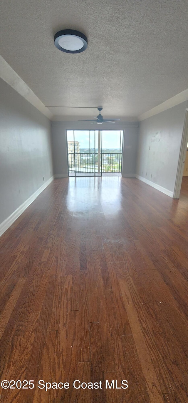 spare room featuring dark wood-style flooring, a textured ceiling, baseboards, and ceiling fan