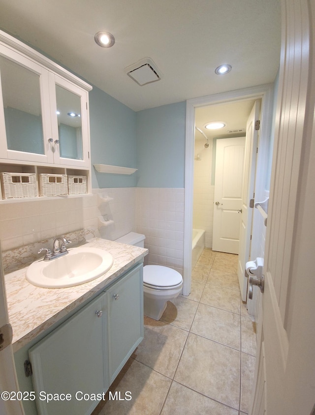 bathroom featuring vanity, shower / bath combination, toilet, tile walls, and tile patterned flooring