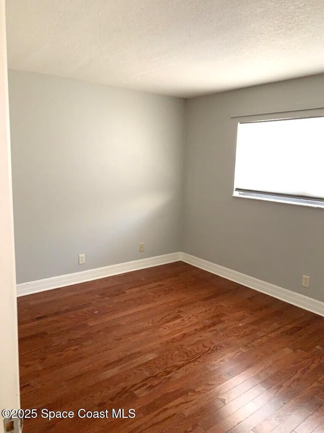unfurnished room with dark wood-style floors, baseboards, and a textured ceiling