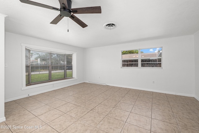 empty room featuring plenty of natural light, light tile patterned floors, ceiling fan, baseboards, and ornamental molding