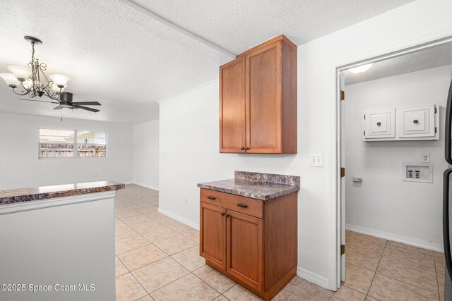 kitchen with light tile patterned flooring, dark countertops, a chandelier, brown cabinets, and a textured ceiling