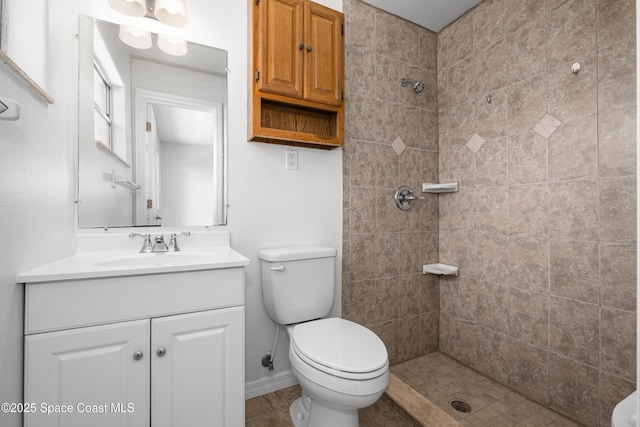 full bath with tiled shower, vanity, toilet, and baseboards