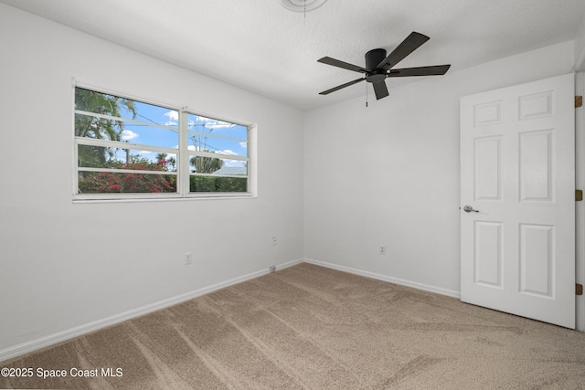 carpeted empty room featuring a ceiling fan and baseboards