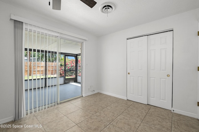 unfurnished bedroom featuring access to exterior, baseboards, tile patterned floors, and a closet