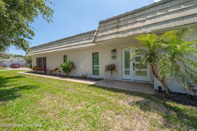 entrance to property with a yard, stucco siding, and mansard roof