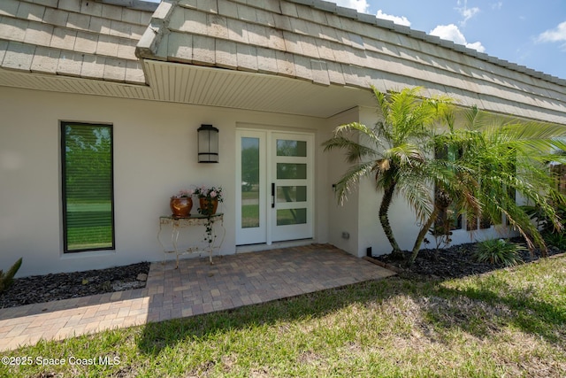 entrance to property with stucco siding and a patio area