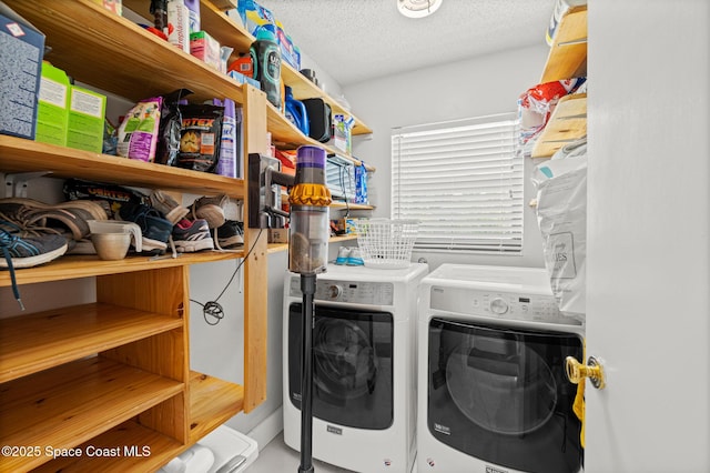 laundry area with washing machine and clothes dryer and a textured ceiling