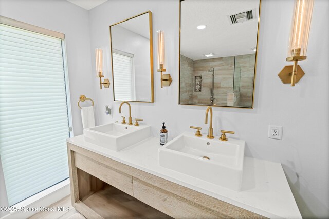 full bathroom featuring a tile shower and double vanity