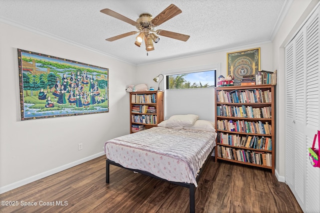 bedroom with wood finished floors, ornamental molding, a textured ceiling, baseboards, and a closet