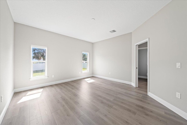 empty room featuring baseboards, visible vents, and wood finished floors