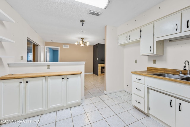 1554 Nona St NE, Palm Bay, FL 32907 - kitchen with a sink, light tile patterned floors, white cabinetry, a peninsula, and a chandelier