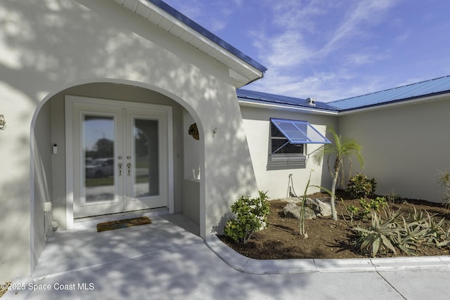 doorway to property featuring metal roof, stucco siding, and french doors