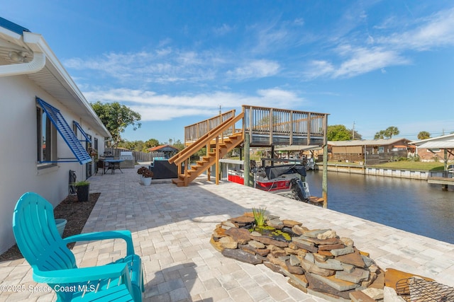 view of patio / terrace featuring a water view, stairway, and fence