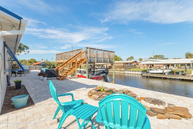 view of patio with fence, a deck with water view, and stairs