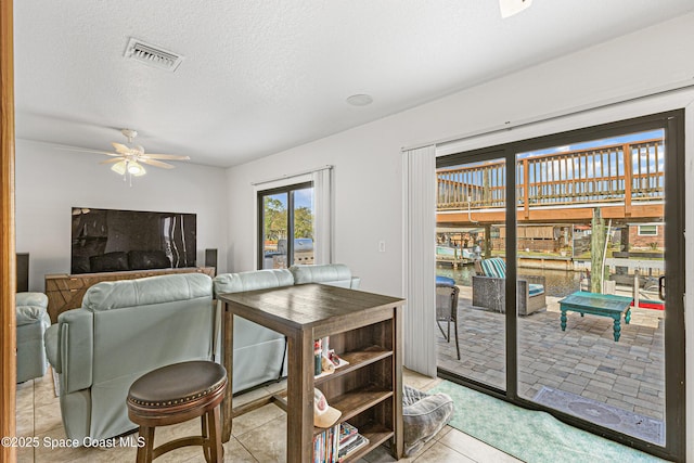 dining space with light tile patterned floors, ceiling fan, visible vents, and a textured ceiling