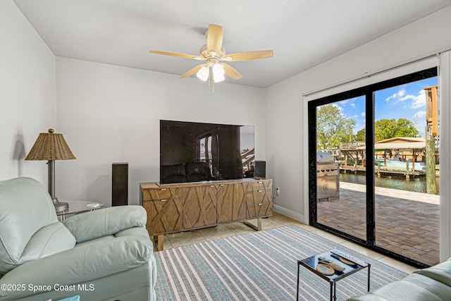 living room with baseboards, ceiling fan, and light tile patterned flooring