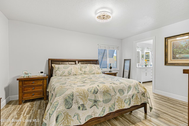 bedroom featuring baseboards, ensuite bath, and wood finished floors