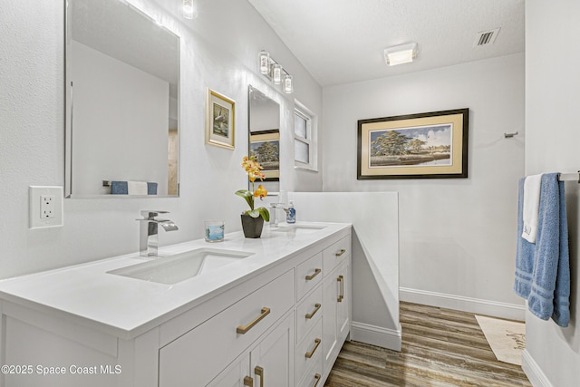 full bath with baseboards, visible vents, a sink, and wood finished floors