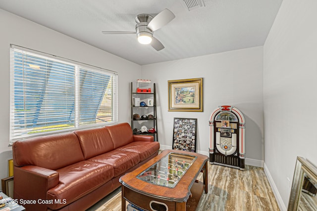 living room featuring baseboards, ceiling fan, visible vents, and light wood-type flooring
