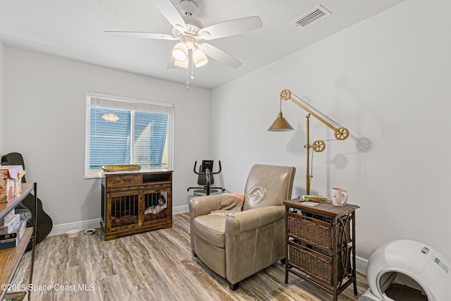 sitting room with a ceiling fan, baseboards, visible vents, and wood finished floors