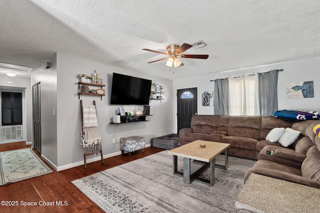 living area with ceiling fan, wood finished floors, baseboards, a textured ceiling, and attic access