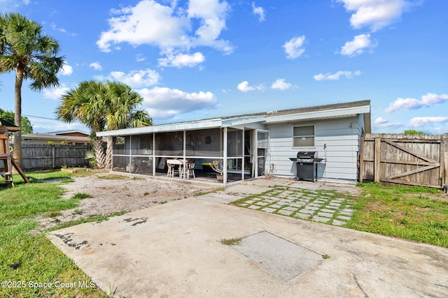 back of house featuring a sunroom, a patio area, a fenced backyard, and a gate